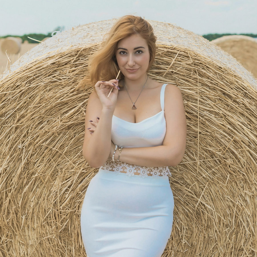 A woman in a white dress posing in front of Breast Augmentation by Dr. Jack Peterson.
