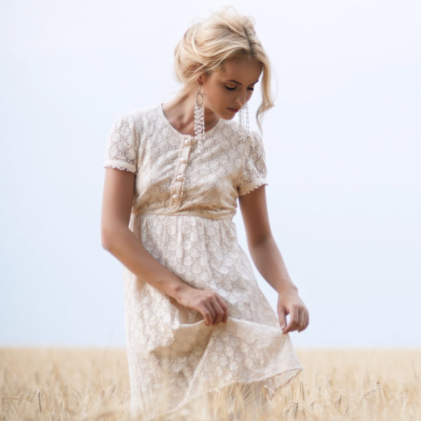A woman in a white dress standing in a wheat field underwent breast reduction surgery under the care of Dr. Jack Peterson, a plastic surgeon.
