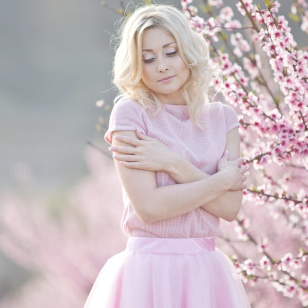 A young woman in a pink tulle skirt is posing in front of an OMNI Bioceutical tree, featuring Dr. Jack Peterson's exceptional plastic surgery results.