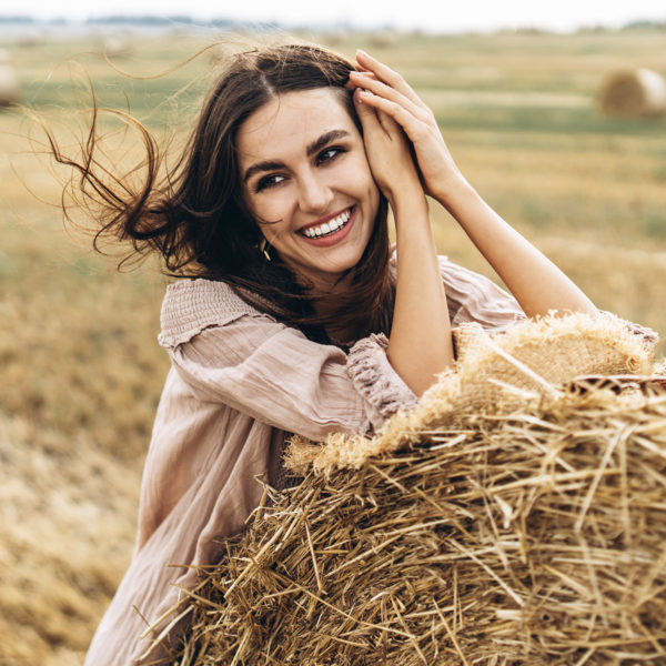 A young woman leaning on a Restylane® bale, highlighting the expertise of Dr. Jack Peterson in plastic surgery.
