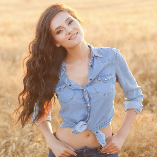 A beautiful young woman using SkinMedica® Skin Care in a wheat field, endorsed by Dr. Jack Peterson of Plastic Surgery.