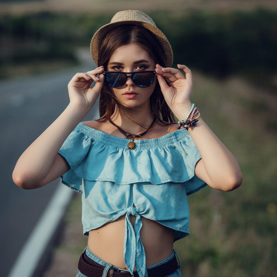 A young woman wearing sunglasses on a country road.
