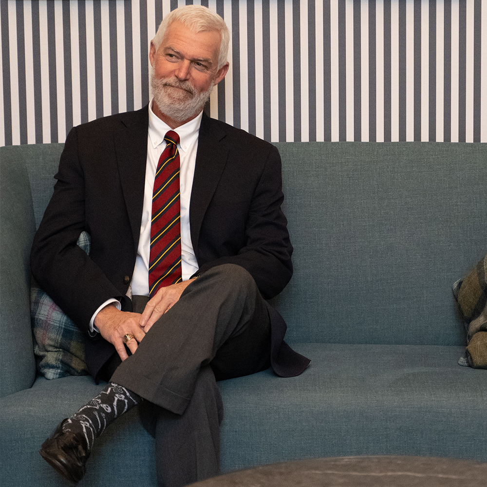 Dr. Jack Peterson, a man in a suit, sits on a blue couch.
