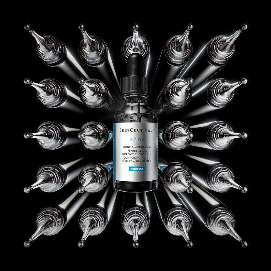 A bottle of P-TIOX, infused with SkinCeuticals Phyto+, is surrounded by multiple glass dropper bottles arranged in a circular pattern on a black background.
