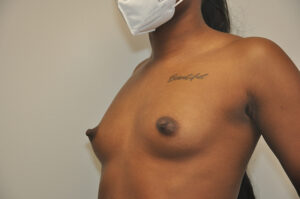 A person wearing a face mask is shown from the side with a visible "Beautiful" tattoo on their upper chest. Their torso and chest are exposed.